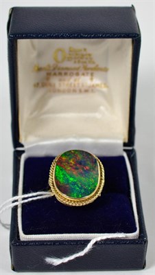 Lot 225 - A 9 carat gold boulder opal ring, an oval cabochon opal in a rubbed over setting within a rope...