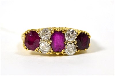 Lot 249 - An 18 carat gold ruby and diamond ring, three graduated oval cut rubies spaced by pairs of old...