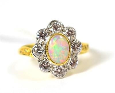 Lot 256 - An 18 carat gold opal and diamond cluster ring, an oval cabochon opal in a milgrain setting, within