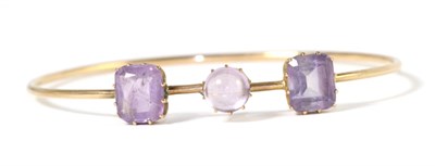 Lot 259 - An early twentieth century amethyst bangle, a round cabochon amethyst spaced by two octagonal...