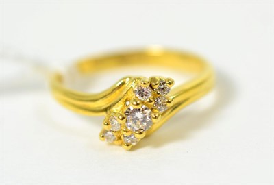 Lot 270 - An 18 carat gold diamond ring, a round brilliant cut diamond spaced by clusters of smaller...