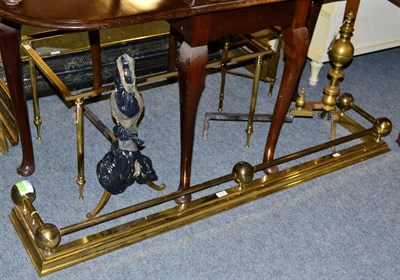 Lot 1192 - Two coffee tables (glass tops missing); a brass fender and a pair of brass fire dogs (5)