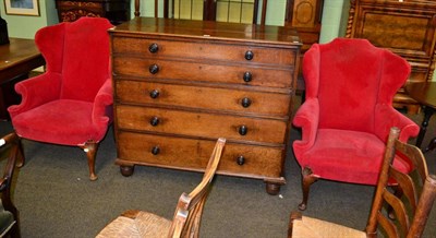 Lot 1321 - A pair of Georgian style wing backed armchairs, upholstered in red fabric, on pad feet