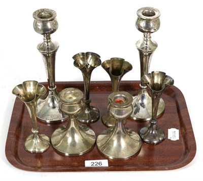 Lot 226 - Two pairs of silver candlesticks of a similar design; and a set of four silver posy vases, the...