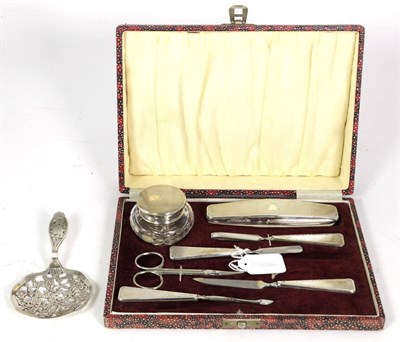 Lot 282 - An Art Deco silver mounted engine turned manicure set in fitted case and a pierced silver spoon (2)