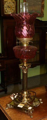 Lot 367 - A reproduction cranberry glass and brass table lamp, in the form of an oil lamp (converted)
