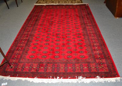 Lot 1217 - A machine made rug of Turkmen design, the crimson field with rows of guls enclosed by multiple...