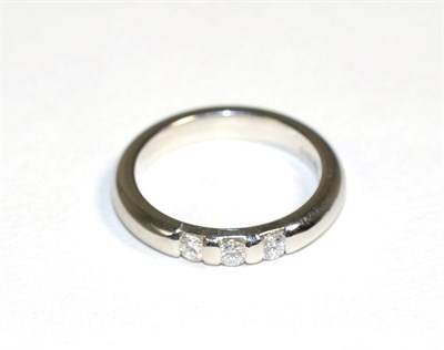 Lot 177 - A platinum diamond three stone ring, three channel set round brilliant cut diamonds, to a...