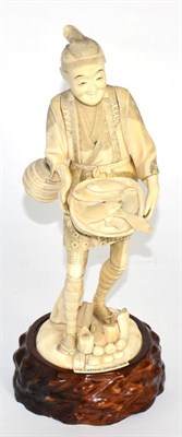 Lot 250 - An ivory okimono figure of a gentleman holding a basket of fish, circa 1900 (a.f.)
