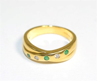 Lot 310 - An 18 carat gold emerald and diamond ring, a crossover band inset with three round cut emeralds and