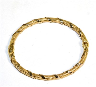 Lot 327 - A twisted motif bangle, with a textured and bright polished design, measures 5cm by 6cm inner...