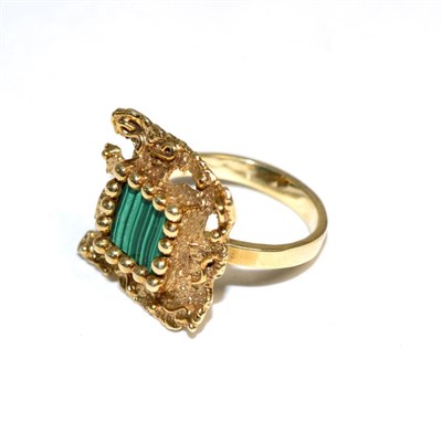 Lot 403 - A malachite ring, a square malachite plaque in a beaded claw setting, within a textured square...