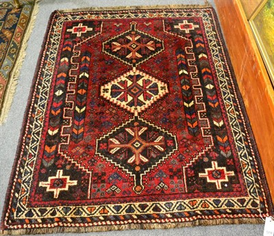 Lot 1218 - Shiraz rug, South West Iran, the claret field with three stepped medallions framed by narrow...