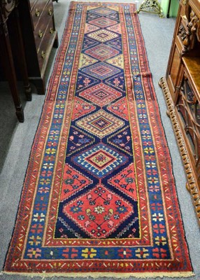 Lot 1220 - North West Persia runner, the indigo field with a column of diamond medallions enclosed by pale...