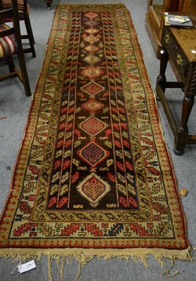 Lot 1235 - North West Persia runner, circa 1920, the chocolate brown field with a column of medallions...