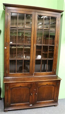 Lot 1328 - A reproduction oak bookcase, with a bold cornice above glazed doors enclosing three adjustable...