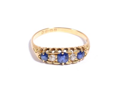 Lot 84 - An 18 carat gold sapphire and diamond ring, three graduated round cut sapphires spaced by old...