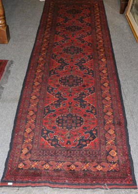 Lot 1290 - Narrow Afghan runner, the madder field with a row of indigo medallions framed by narrow...