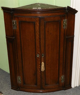 Lot 1354 - A George III oak bow front corner cupboard