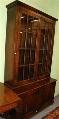 Lot 1355 - A reproduction oak bookcase, with a bold cornice above glazed doors enclosing three adjustable...