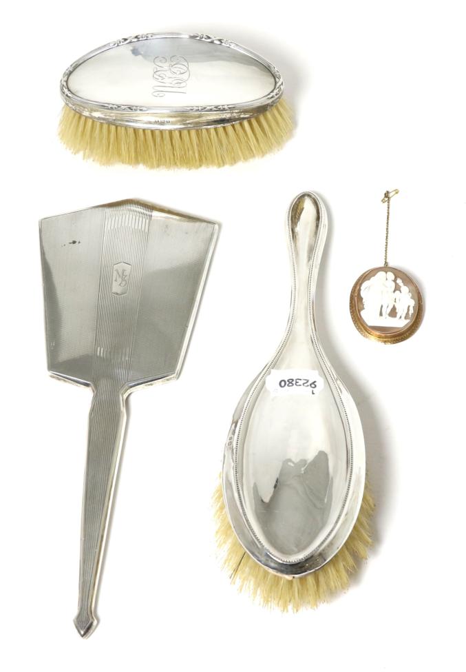 Lot 1 - A carved shell cameo brooch; an Art Deco silver hand mirror; and two silver dressing table brushes