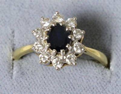 Lot 5 - An 18 carat gold sapphire and diamond cluster ring, an oval cut sapphire within a border of...