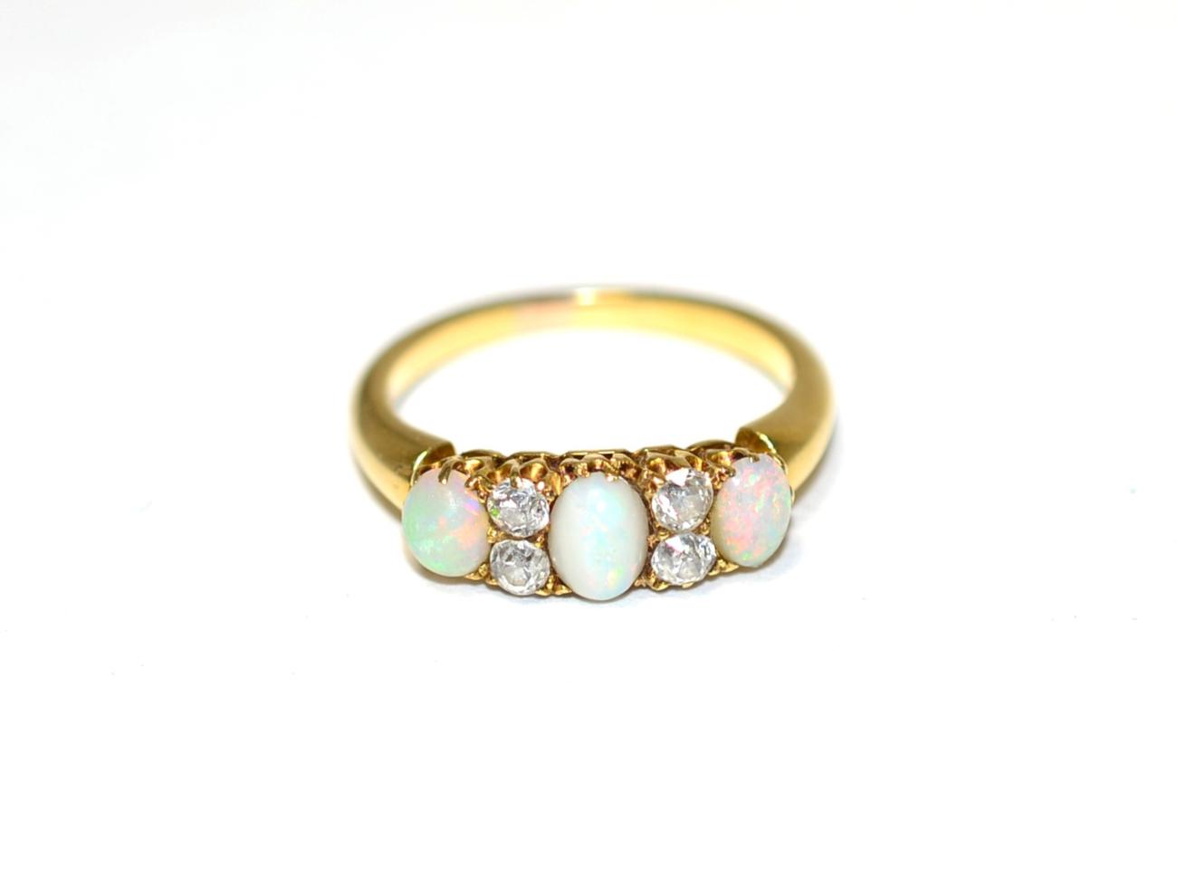 Lot 267 - An opal and diamond ring, three oval cabochon opals, spaced by pairs of old cut diamonds, total...