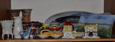 Lot 250 - A shelf of ceramics including; Highland stoneware dishes, Coalport cottages, Belleek vases,...