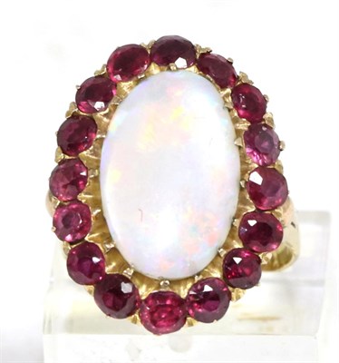 Lot 282 - An opal and ruby cluster ring, an oval cabochon opal within a border of round cut rubies, to forked