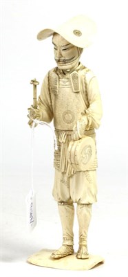 Lot 348 - A Japanese ivory okimono, 19th century, as a Samurai holding a Mitzu Tomoe drum and beater, on...