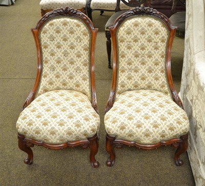 Lot 1170 - A pair of Victorian walnut upholstered nursing chairs