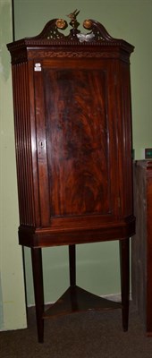 Lot 1209 - A late Georgian mahogany straight front hanging corner cupboard with fret carved pediment and later