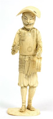 Lot 118 - A Japanese ivory okimono, 19th century, as a Samurai holding a Mitzu Tomoe drum and beater, on...