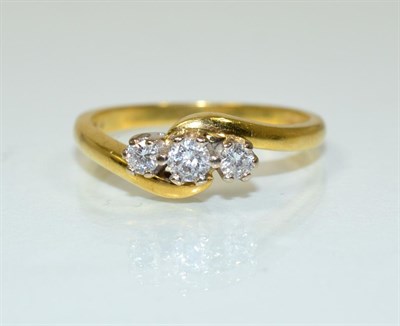 Lot 198 - An 18 carat gold diamond three stone ring, a round brilliant cut diamond spaced by two smaller...