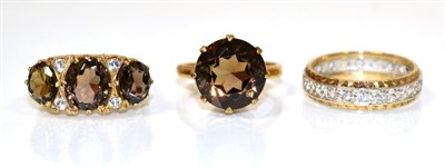 Lot 216 - A 9 carat gold smokey quartz and cubic zirconia ring, three graduated smokey quartz spaced by pairs