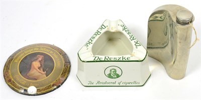 Lot 262 - An advertising ashtray together with an advertising paperweight and a white metal hip flask (3)