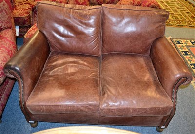 Lot 1178 - A studded brown leather two seater sofa