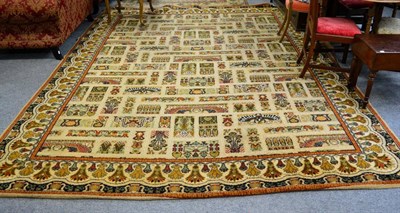 Lot 1253 - A machine made carpet, the pale camel field with winged motifs enclosed by floral borders, 338cm by