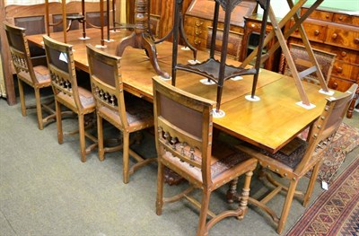 Lot 1380 - A French oak draw leaf dining table with eight embossed leather dining chairs