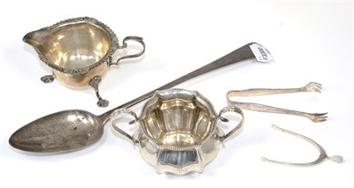 Lot 210 - ~ A small group of silver comprising a Georgian basting spoon, wishbone form sugar nips, a...