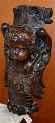 Lot 274 - ~ A carved oak furniture element in the form of a putto, 50cm high