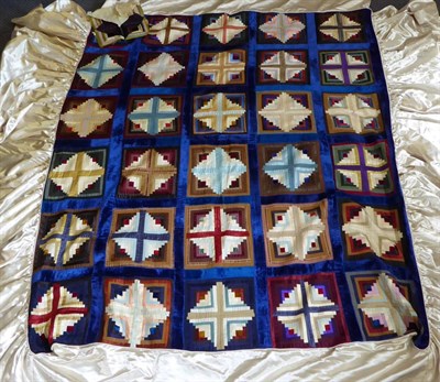 Lot 1270 - Early 20th century silk log cabin patchwork bed cover, within a blue velvet frame, attached...