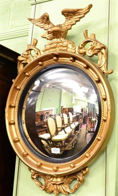 Lot 1293 - A reproduction eagle surmounted gilt convex mirror in the Regency style, with ebonised slip