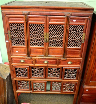 Lot 1304 - Chinese hardwood cabinet with pierced doors and sliding panels, fitted three central drawers