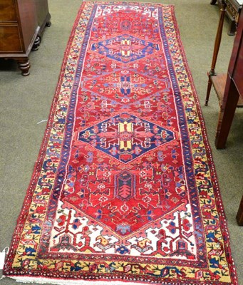 Lot 1353 - Heriz Runner, Iranian Azerbaijan, the blood red field with a column of medallions enclosed by...