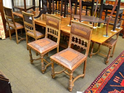 Lot 1432 - ~ A French oak draw-leaf dining table with eight embossed leather dining chairs