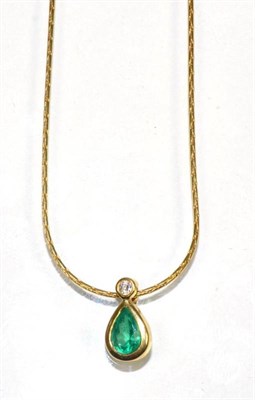Lot 138 - An 18 carat gold emerald and diamond pendant, a round brilliant cut diamond above a pear cut...