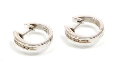 Lot 323 - A pair of 18 carat white gold diamond hoop earrings, channel set with round brilliant cut diamonds