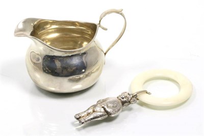 Lot 342 - A silver cream jug together with a white metal bear form rattle on a plastic teething ring (2)