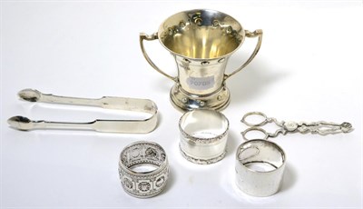 Lot 35 - A silver twin handled loving cup in the Arts & Crafts taste, together with three silver napkin...